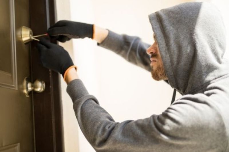 Persona forzando la cerradura de una puerta con un destornillador, representando la usurpación de inmuebles.