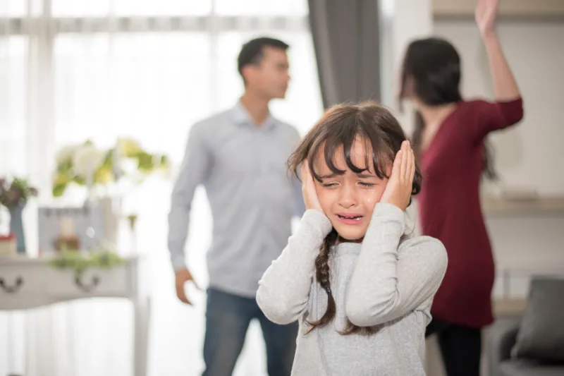 Niña angustiada durante una discusión de sus padres en proceso de divorcio