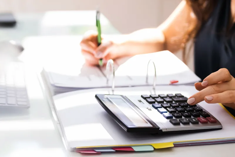 impuesto sucesiones png - Impuesto de sucesiones en España: ¿Cuánto hay que pagar por una herencia? Persona calculando impuestos con una calculadora y documentos contables.