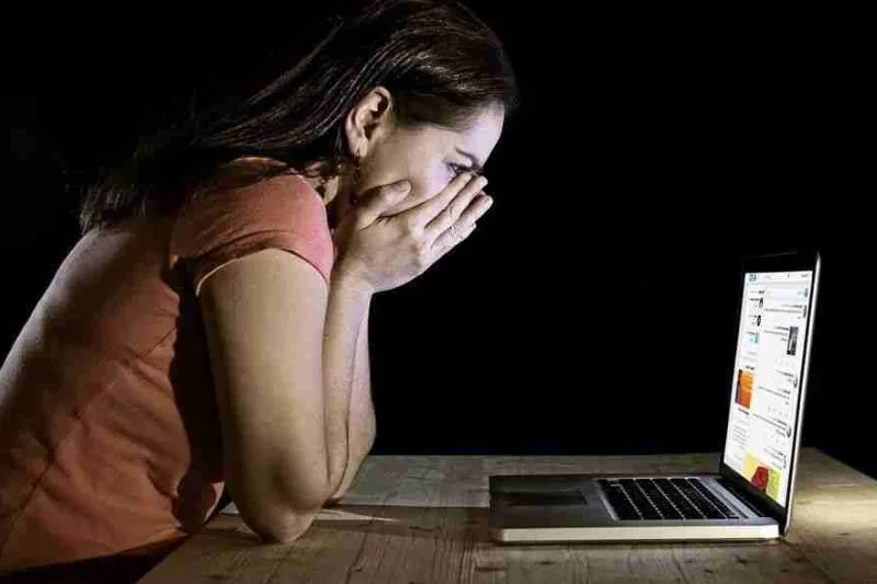 Mujer angustiada frente al ordenador tras sufrir un delito contra la intimidad en internet