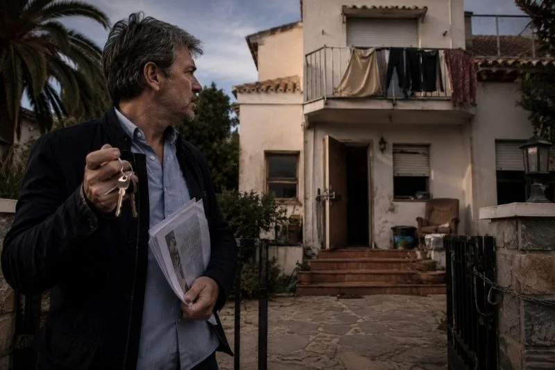 Hombre preocupado frente a una segunda vivienda ocupada